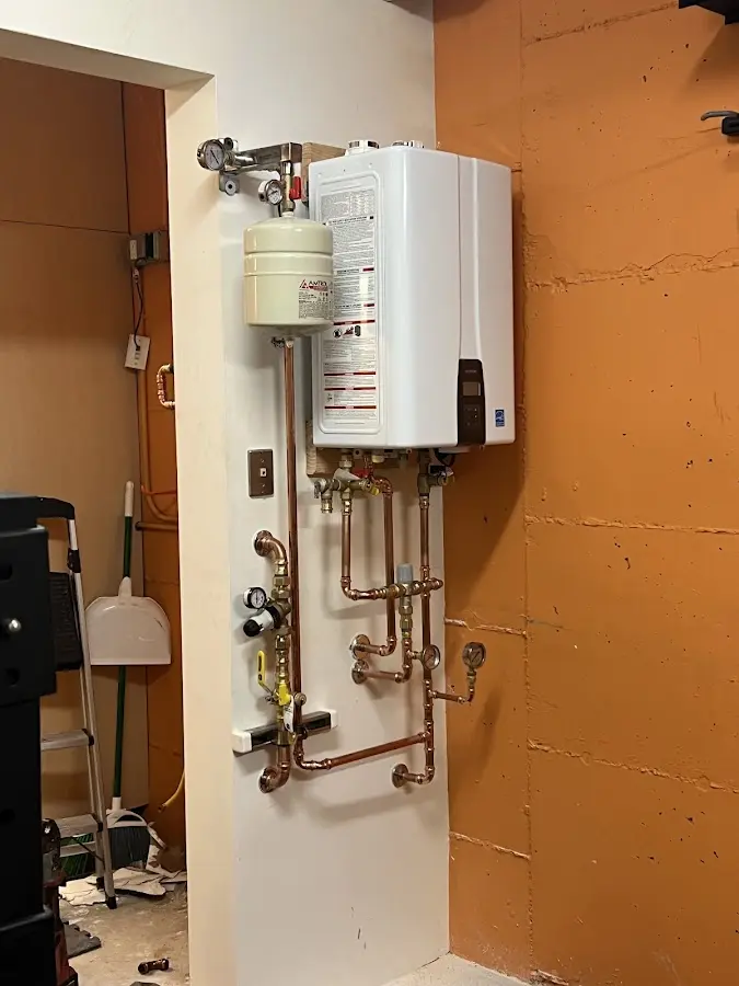 Plumbing technician inspecting water heater connections in American Falls